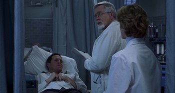 Movie still from “Hellraiser: Hellseeker” (2002), directed by Rick Bota – A man in a hospital bed with two other doctors; Medium shot, Over the shoulder angle