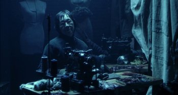 Movie still from “Hellraiser: Hellseeker” (2002), directed by Rick Bota – A person sitting at a table with a sewing machine; Medium shot, High angle