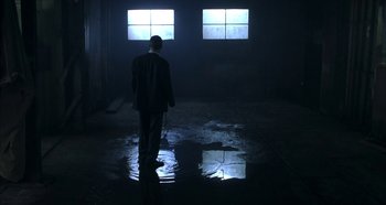 Movie still from “Hellraiser: Hellseeker” (2002), directed by Rick Bota – A man in a suit standing in a dark room; Wide shot, Low angle