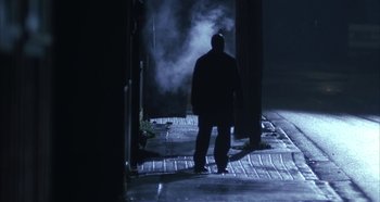 Movie still from “Hellraiser: Hellseeker” (2002), directed by Rick Bota – A man standing on the side of the street in the dark; Wide shot, Low angle