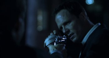 Movie still from “Hellraiser: Hellseeker” (2002), directed by Rick Bota – A man holding a camera in a dark room at night; Close Up shot, Over the shoulder angle