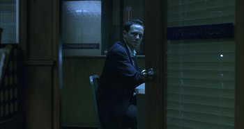 Movie still from “Hellraiser: Hellseeker” (2002), directed by Rick Bota – A man sitting in a chair in front of an open door; Medium shot, Over the shoulder angle