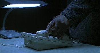 Movie still from “Hellraiser: Hellseeker” (2002), directed by Rick Bota – A person using a telephone on a desk; Extreme Close Up shot, Low angle