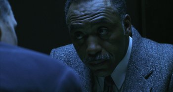 Movie still from “Hellraiser: Hellseeker” (2002), directed by Rick Bota – An older man in a suit and tie looking down; Close Up shot, Over the shoulder angle
