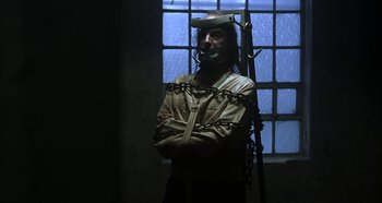 Movie still from “Hellraiser: Hellseeker” (2002), directed by Rick Bota – A man in chains standing next to a window; Medium shot, Low angle
