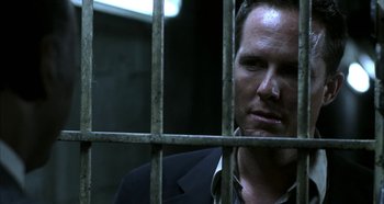 Movie still from “Hellraiser: Hellseeker” (2002), directed by Rick Bota – A man standing behind a metal fence looking at the camera; Close Up shot, Over the shoulder angle