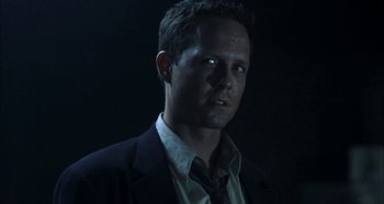 Movie still from “Hellraiser: Hellseeker” (2002), directed by Rick Bota – A man wearing a suit and tie standing in a dark room; Close Up shot, Low angle