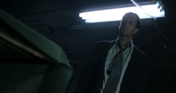 Movie still from “Hellraiser: Hellseeker” (2002), directed by Rick Bota – A man in a suit and tie standing in a dark room; Medium shot, Low angle