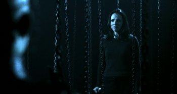 Movie still from “Hellraiser: Hellseeker” (2002), directed by Rick Bota – A woman standing in a dark room behind chains; Medium shot, Low angle