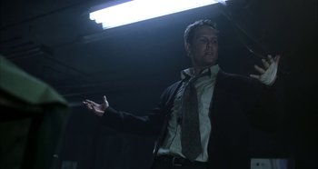 Movie still from “Hellraiser: Hellseeker” (2002), directed by Rick Bota – A man wearing a suit and tie standing in a dark room; Medium shot, Low angle