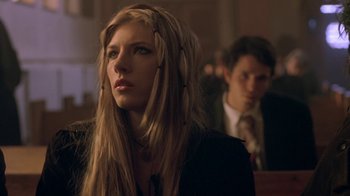 Movie still from “Hellraiser: Hellworld” (2005), directed by Rick Bota – A woman with long blonde hair wearing headphones in front of a man; Close Up shot, Low angle