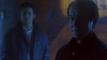Movie still from “Hellraiser: Hellworld” (2005), directed by Rick Bota – Two men standing in a dark room , one of whom is wearing a black jacket; Close Up shot, Over the shoulder angle