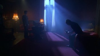Movie still from “Hellraiser: Hellworld” (2005), directed by Rick Bota – Two people are standing in a dark room with a lamp; Wide shot, Low angle