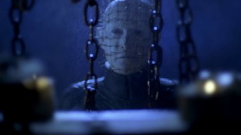 Movie still from “Hellraiser: Hellworld” (2005), directed by Rick Bota – A person with a face mask and chains hanging from the side of a window; Close Up shot, Low angle