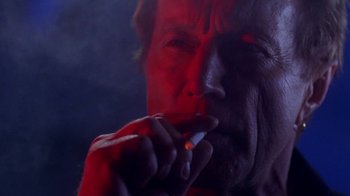 Movie still from “Hellraiser: Hellworld” (2005), directed by Rick Bota – An older man smoking a cigarette in a dark room; Close Up shot, Low angle