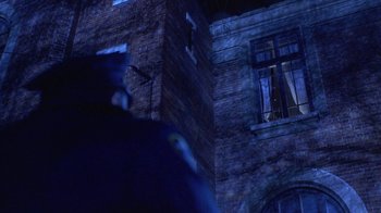 Movie still from “Hellraiser: Hellworld” (2005), directed by Rick Bota – A person standing in front of a brick building at night; Wide shot, Low angle
