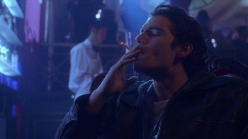 Movie still from “Hellraiser: Hellworld” (2005), directed by Rick Bota – A young man smoking a cigarette in a dark room; Close Up shot, Over the shoulder angle