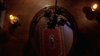 Movie still from “Hellraiser: Hellworld” (2005), directed by Rick Bota – A person is sitting in a chair on a rug; Extreme Wide shot, Overhead angle