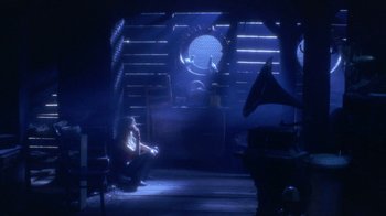 Movie still from “Hellraiser: Hellworld” (2005), directed by Rick Bota – A person sitting in a room with a record player; Wide shot, High angle