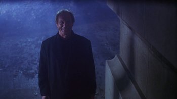 Movie still from “Hellraiser: Hellworld” (2005), directed by Rick Bota – A man in a black jacket standing next to a wall; Medium shot, Low angle