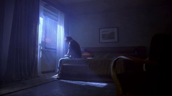 Movie still from “Hellraiser: Hellworld” (2005), directed by Rick Bota – A man sitting on a bed looking out a window; Wide shot, Low angle