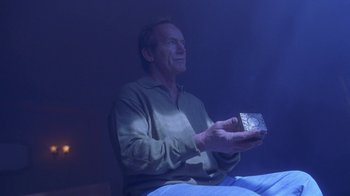 Movie still from “Hellraiser: Hellworld” (2005), directed by Rick Bota – A man sitting on a bed holding a box; Medium shot, Low angle