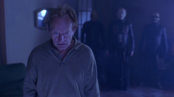 Movie still from “Hellraiser: Hellworld” (2005), directed by Rick Bota – A group of people standing in a dark room; Medium shot, Over the shoulder angle