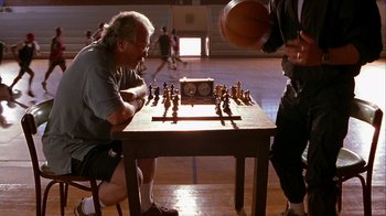 Movie still from “Hellraiser: Inferno” (2000), directed by Scott Derrickson – Two men playing chess in a gymnasium with a basketball; Medium shot, High angle