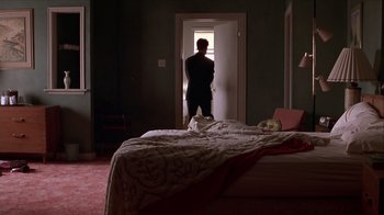 Movie still from “Hellraiser: Inferno” (2000), directed by Scott Derrickson – A man standing in front of a bed in a bedroom; Wide shot, High angle