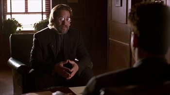 Movie still from “Hellraiser: Inferno” (2000), directed by Scott Derrickson – A man sitting in front of a table talking to a woman; Medium shot, Over the shoulder angle