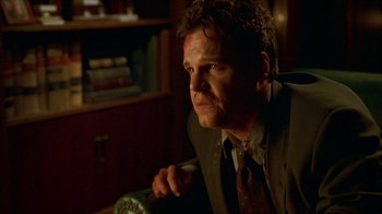 Movie still from “Hellraiser: Inferno” (2000), directed by Scott Derrickson – A man in a suit sitting in front of a book case; Close Up shot, Low angle