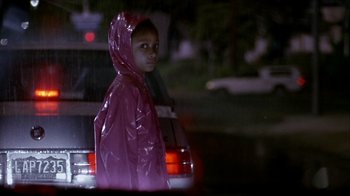 Movie still from “Hellraiser: Inferno” (2000), directed by Scott Derrickson – A young boy in a raincoat standing next to a car; Medium shot, Over the shoulder angle