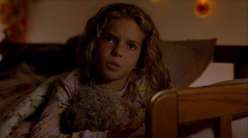 Movie still from “Hellraiser: Inferno” (2000), directed by Scott Derrickson – A young girl sitting on a couch holding a stuffed animal; Close Up shot, High angle