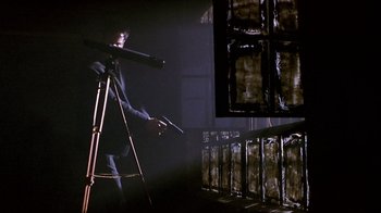 Movie still from “Hellraiser: Inferno” (2000), directed by Scott Derrickson – A man standing in a dark room holding a telescope; Wide shot, Low angle