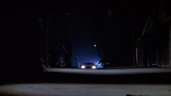 Movie still from “Hellraiser: Inferno” (2000), directed by Scott Derrickson – A car driving down a street at night; Extreme Wide shot, Low angle