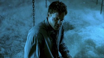 Movie still from “Hellraiser: Inferno” (2000), directed by Scott Derrickson – A man in a shirt and tie standing next to chains; Medium shot, Low angle