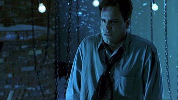 Movie still from “Hellraiser: Inferno” (2000), directed by Scott Derrickson – A man wearing a neck tie standing next to chains; Medium shot, Low angle