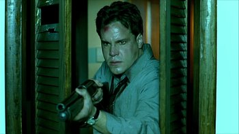 Movie still from “Hellraiser: Inferno” (2000), directed by Scott Derrickson – A man holding a gun while standing in front of a window; Close Up shot, Low angle