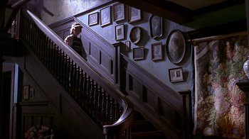 Movie still from “Hellraiser: Inferno” (2000), directed by Scott Derrickson – A man sitting on top of a wooden stair case; Wide shot, High angle