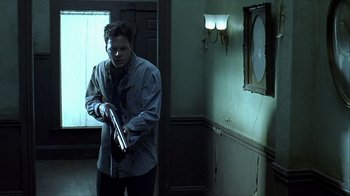 Movie still from “Hellraiser: Inferno” (2000), directed by Scott Derrickson – A man holding a gun while standing next to a wall; Medium shot, Low angle