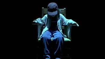 Movie still from “Hellraiser: Inferno” (2000), directed by Scott Derrickson – A person sitting in a chair wearing a hat; Medium shot, High angle