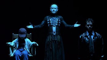 Movie still from “Hellraiser: Inferno” (2000), directed by Scott Derrickson – A man in a body suit and some people in a dark room; Medium shot, Low angle