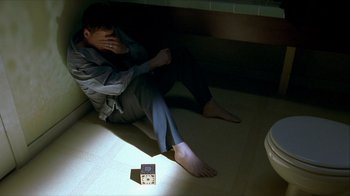 Movie still from “Hellraiser: Inferno” (2000), directed by Scott Derrickson – A man sitting on the floor in the dark; Medium shot, High angle