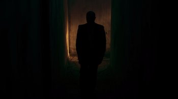 Movie still from “Hellraiser: Judgment” (2018), directed by Gary J. Tunnicliffe – A man in a suit standing in the dark; Wide shot, Low angle