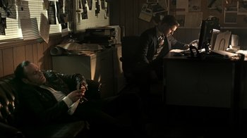 Movie still from “Hellraiser: Judgment” (2018), directed by Gary J. Tunnicliffe – A man sitting at a desk in front of a laptop; Wide shot, High angle