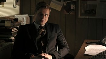 Movie still from “Hellraiser: Judgment” (2018), directed by Gary J. Tunnicliffe – A man wearing a suit and tie sitting in a chair; Medium shot, Over the shoulder angle