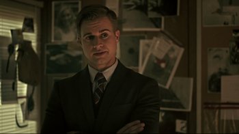 Movie still from “Hellraiser: Judgment” (2018), directed by Gary J. Tunnicliffe – A man wearing a suit and tie standing in a room; Close Up shot, Over the shoulder angle