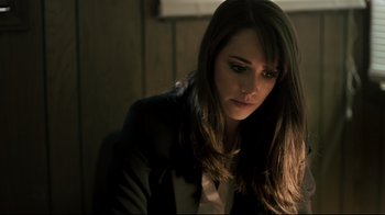 Movie still from “Hellraiser: Judgment” (2018), directed by Gary J. Tunnicliffe – A woman in a black jacket is sitting in a dark room; Close Up shot, High angle