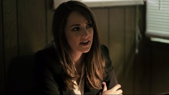 Movie still from “Hellraiser: Judgment” (2018), directed by Gary J. Tunnicliffe – A woman in a black jacket is sitting in a dark room; Close Up shot, Over the shoulder angle