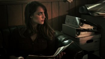 Movie still from “Hellraiser: Judgment” (2018), directed by Gary J. Tunnicliffe – A woman sitting in a chair holding a magazine; Close Up shot, Over the shoulder angle